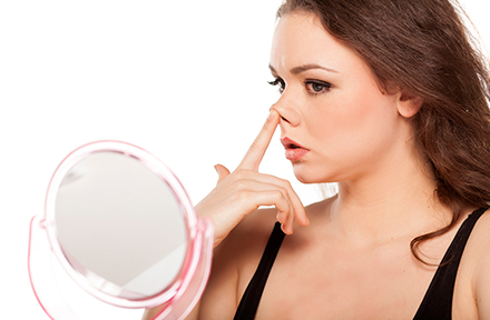 Mujer tocndose la punta de la nariz frente al espejo 